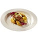 A Solia white round sugarcane plate with meat and vegetables on it.