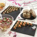 A Solia slate black tray on a table with food on it.