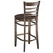 A Lancaster Table & Seating wood ladder back bar stool with a dark brown vinyl seat.