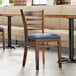 A Lancaster Table & Seating wooden ladder back chair with a detached blue vinyl seat