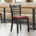 A Lancaster Table & Seating black wood ladder back chair with a burgundy vinyl seat