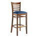 A Lancaster Table & Seating wooden bar stool with a navy vinyl seat.