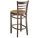 A Lancaster Table & Seating wooden bar stool with a light brown cushioned seat.