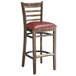 A Lancaster Table & Seating wooden ladder back bar stool with a burgundy vinyl seat.