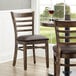 Two Lancaster Table & Seating vintage wood ladder back chairs with dark brown vinyl seats on a table in a restaurant dining area.