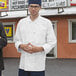 Two men standing outside a restaurant with a man wearing an Uncommon Chef white long sleeve chef coat.