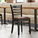 A Lancaster Table & Seating wood ladder back restaurant chair with a dark brown cushion on the seat.