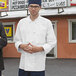 A man wearing a Uncommon Chef long sleeve white chef coat.