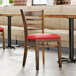A Lancaster Table & Seating wood chair with a red vinyl seat