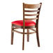 A Lancaster Table & Seating wooden ladder back chair with a red vinyl seat.
