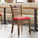 A Lancaster Table & Seating wooden chair with a red cushion.
