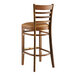 A Lancaster Table & Seating wooden ladder back bar stool with light brown vinyl seat.