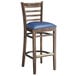 A Lancaster Table & Seating wood ladder back bar stool with a navy vinyl seat.