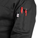 A person wearing a black Uncommon Chef long sleeve chef coat with a tool in the pocket.