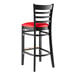 A Lancaster Table & Seating black wood bar stool with a red vinyl seat.