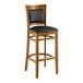 A Lancaster Table & Seating Sofia wooden bar stool with black vinyl seat.