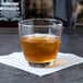 A Libbey old fashioned glass of whiskey on a table with ice.