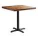 A Lancaster Table & Seating square wood table with a black cast iron base.