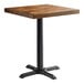 A Lancaster Table & Seating square wooden table with a black cast iron base.