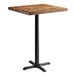 A Lancaster Table & Seating square wooden table with a cast iron base.