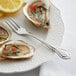 A plate of oysters with a fork and lemon on it.