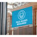 A blue rectangular window decal with white text that says "Mask Required" on a window.