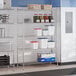 A chrome 5-shelf storage rack with various kitchen containers and supplies placed on the shelves.