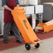 A man pushing an orange Fryclone 40 fryer oil shuttle cart.