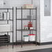A black epoxy 4-shelf wire shelving unit with 54-inch posts, used for storage in a commercial setting.
