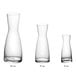 A group of Acopa glass carafes with different sizes.