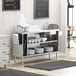 A stainless steel Regency waitress station with shelves holding plates and a sink.