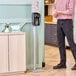 A man standing next to a Kutol Health Guard hand sanitizer station with a sign.