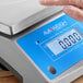 A person using the AvaWeigh digital portion control scale on a counter in a professional kitchen.