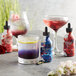 A glass of Wild Hibiscus Rose and Hibiscus Floral Extract next to a variety of drinks.