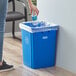 A woman putting a plastic bottle in a blue Lavex recycle bin with a blue label.