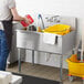 A man in an apron washing a Regency stainless steel utility sink.