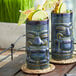 Two blue Tuxton ceramic tiki mugs filled with fruit and umbrellas.