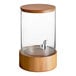 An Acopa glass beverage dispenser with wood lid and base on a wooden stand.