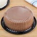 A chocolate cake in a D&W Fine Pack plastic container with a clear dome lid.