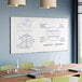 A large wall-mounted melamine whiteboard with an aluminum frame in a conference room setting.