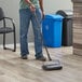 A man using a Lavex triple brush floor sweeper to clean the floor in a professional kitchen.