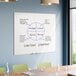 A large frameless frosted glass dry erase board mounted on a wall in a conference room.