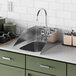 A Waterloo stainless steel drop-in sink with side splashes in a green kitchen with white tile.