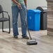 A person using a Lavex single brush floor sweeper in a professional kitchen.
