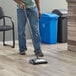 A man using a Lavex dual blade floor sweeper to clean the floor in a professional kitchen.