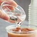 A hand pouring Bossen Liquid Fructose Syrup into a glass of liquid.