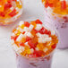 A group of plastic cups of jelly with colorful jelly inside.