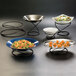 A white bowl of pasta with vegetables on an American Metalcraft wrought iron riser.