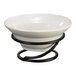 A white bowl on a wrought iron riser with a black wire holder.