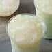 A cup of white coconut jelly topping with chunks in it.